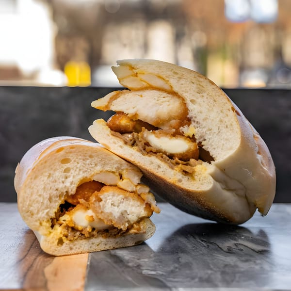 Two halves of a chicken and cheese submarine sandwich on a dark marble surface.