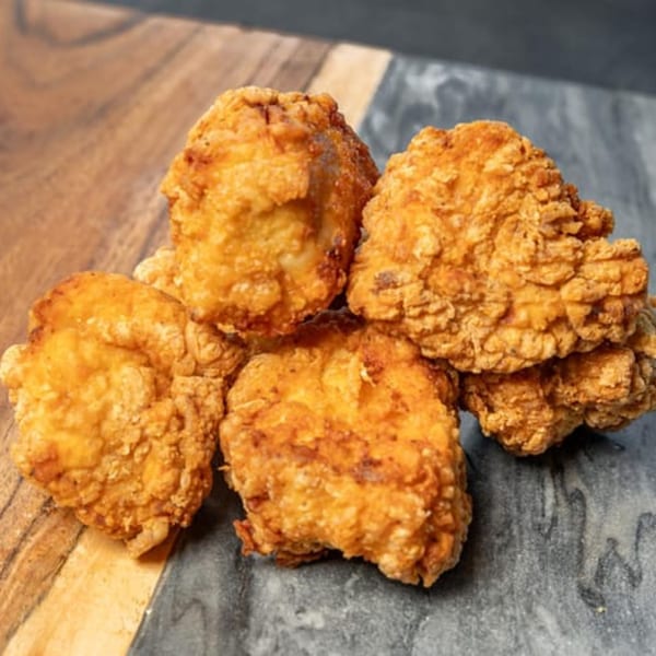 Five pieces of golden-brown fried chicken from CARS Eatery, arranged on a two-toned surface.