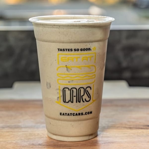 A CARS Eatery milkshake in a branded plastic cup, with a burger logo and "EAT AT CARS" text.