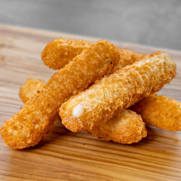 Golden-brown mozzarella sticks, one with melted cheese peeking out, piled on a wooden board.