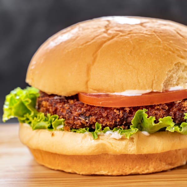 A close-up of a CARS Eatery fast-food burger with a crispy patty, lettuce, tomato, and mayonnaise.