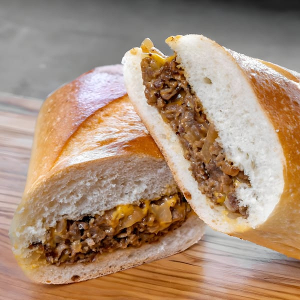 CARS Eatery's cheesesteak sandwich, cut in half, revealing steak, melted cheese, and onions.