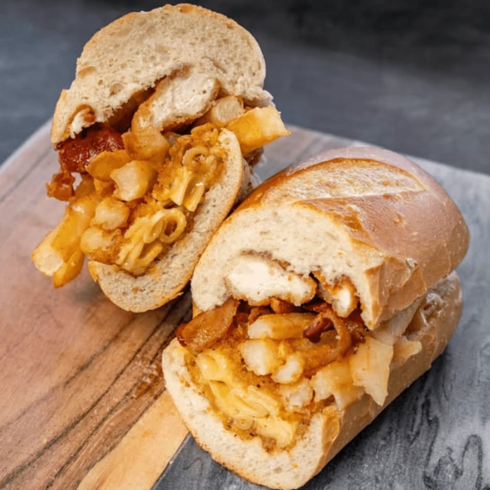 Two halves of a CARS Eatery sandwich, filled with chicken, fries, and mac and cheese.