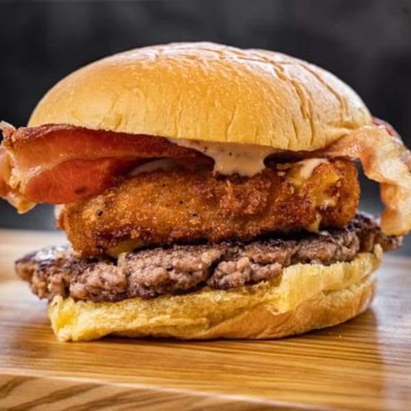 CARS Eatery's burger with two beef patties, a fried cheese patty, bacon, and sauce.