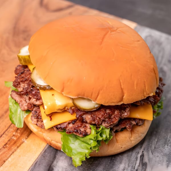 CARS Eatery's double smash burger with melted cheese, pickles, and lettuce on a bun.