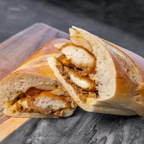 CARS Eatery's fried chicken sandwich, cut in half, revealing crispy chicken and sauce on a baguette.