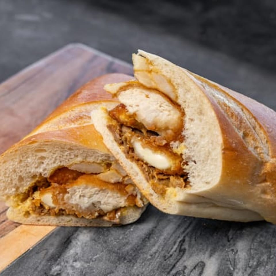 CARS Eatery's fried chicken sandwich, cut in half, revealing crispy chicken and sauce on a baguette.