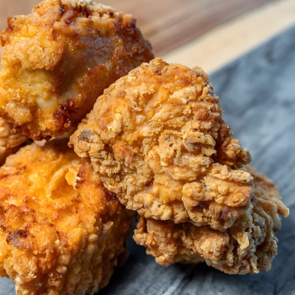 Close-up of golden-brown, crispy fried chicken pieces from CARS Eatery, piled on a dark surface.