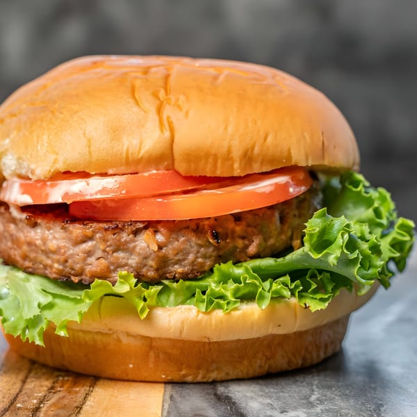 A CARS Eatery burger with a thick patty, lettuce, tomato, and white sauce on a bun.