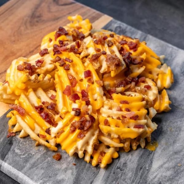 CARS Eatery's waffle fries are loaded with melted cheese and crispy bacon bits on a marble slab.